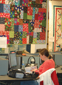 a student studying in the MSUB library with a colorful quilt hanging on a nearby wall.