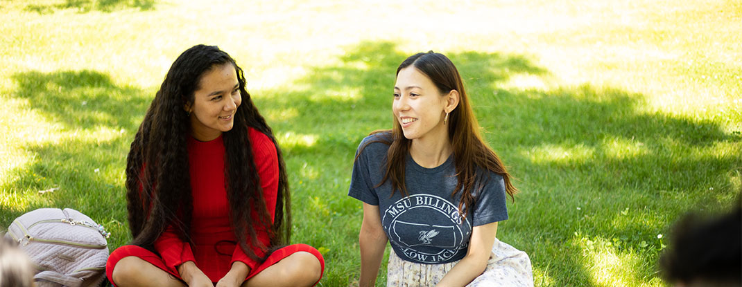 Two students sitting outside on the grass