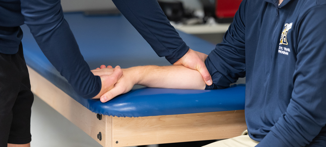 athletic trainer moving wrist of student