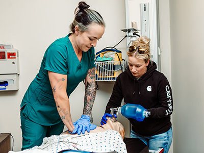 two nursing students apply oxygen bag to dummy