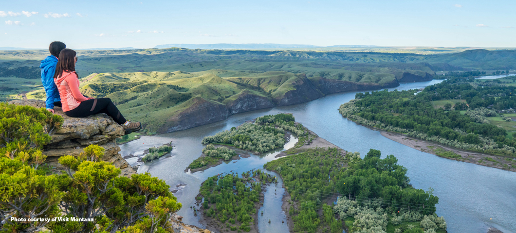couple sitting on cliff above Yellowstone River; photo courtesy of Visit Montana