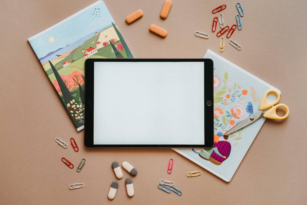 blank tablet with two closed notebookes, scirrors and loose paper clips