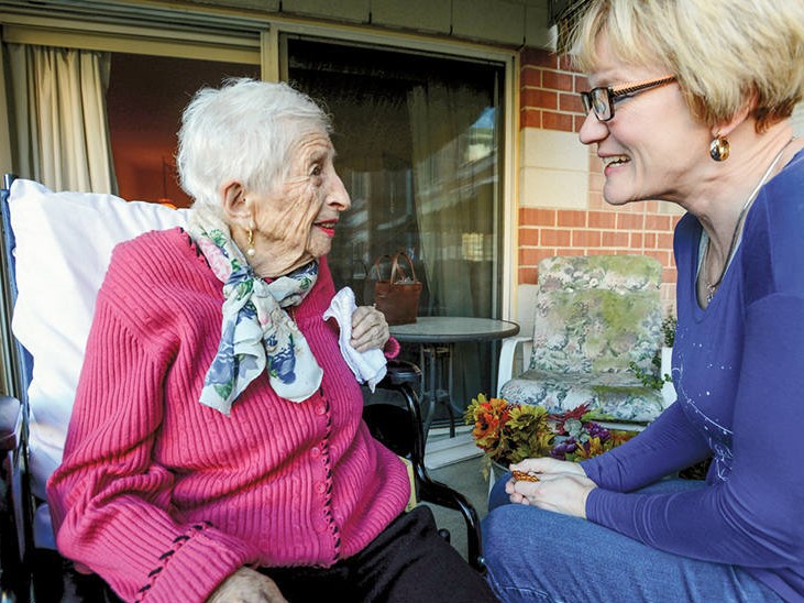 hospice volunteer visits with elderly woman on a porch