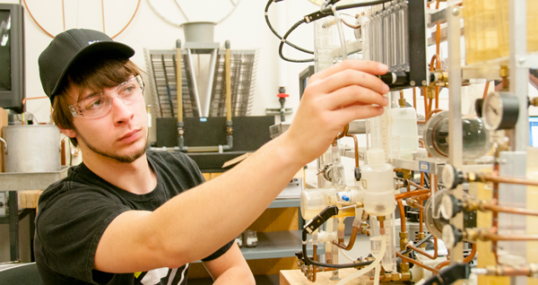 young man in safety goggles adjusting a valve