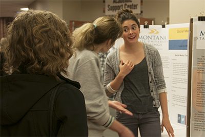 a student explains her research project to onlookers