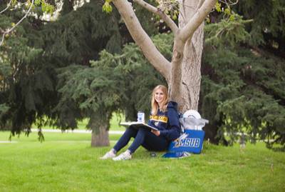 student relaxing by tree