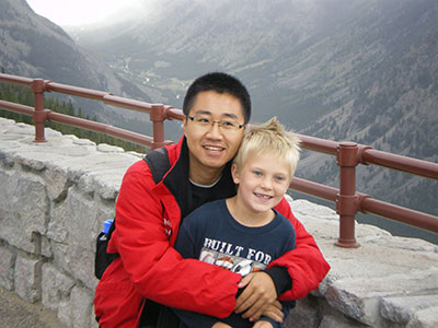 A student poses with a youth near a mountain range