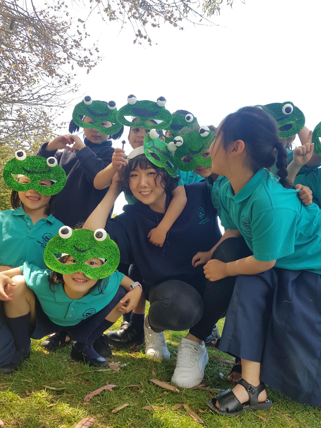 student teacher with elementary students in glittery frog masks