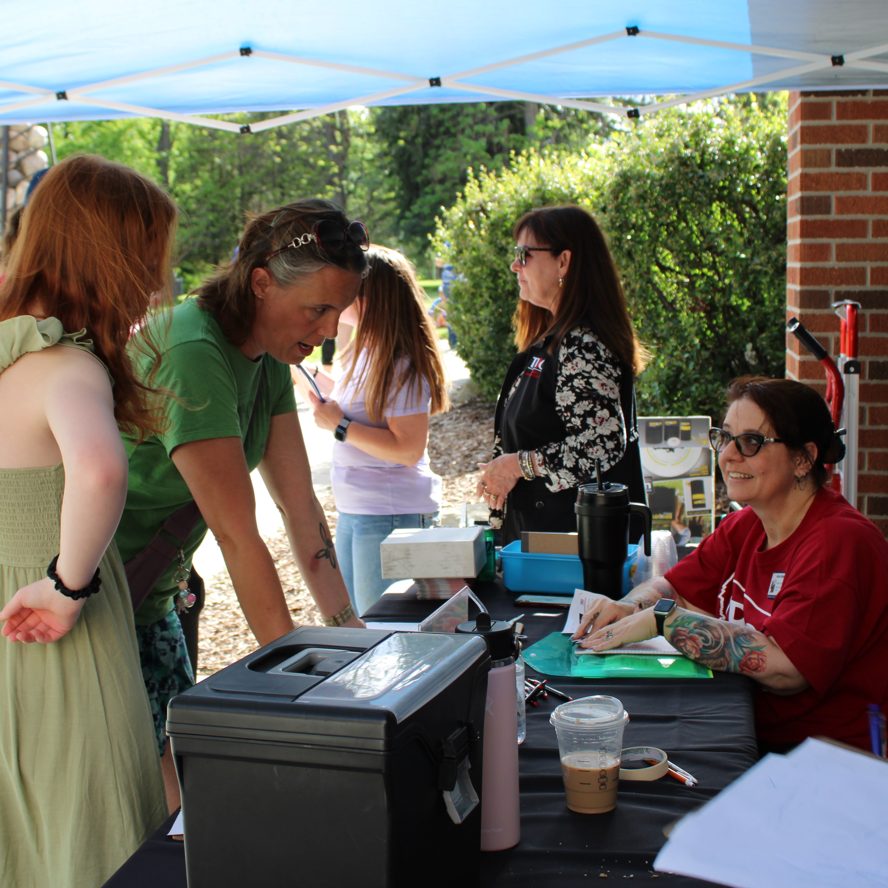 TRIO EOC staff talking with a woman in a green shirt