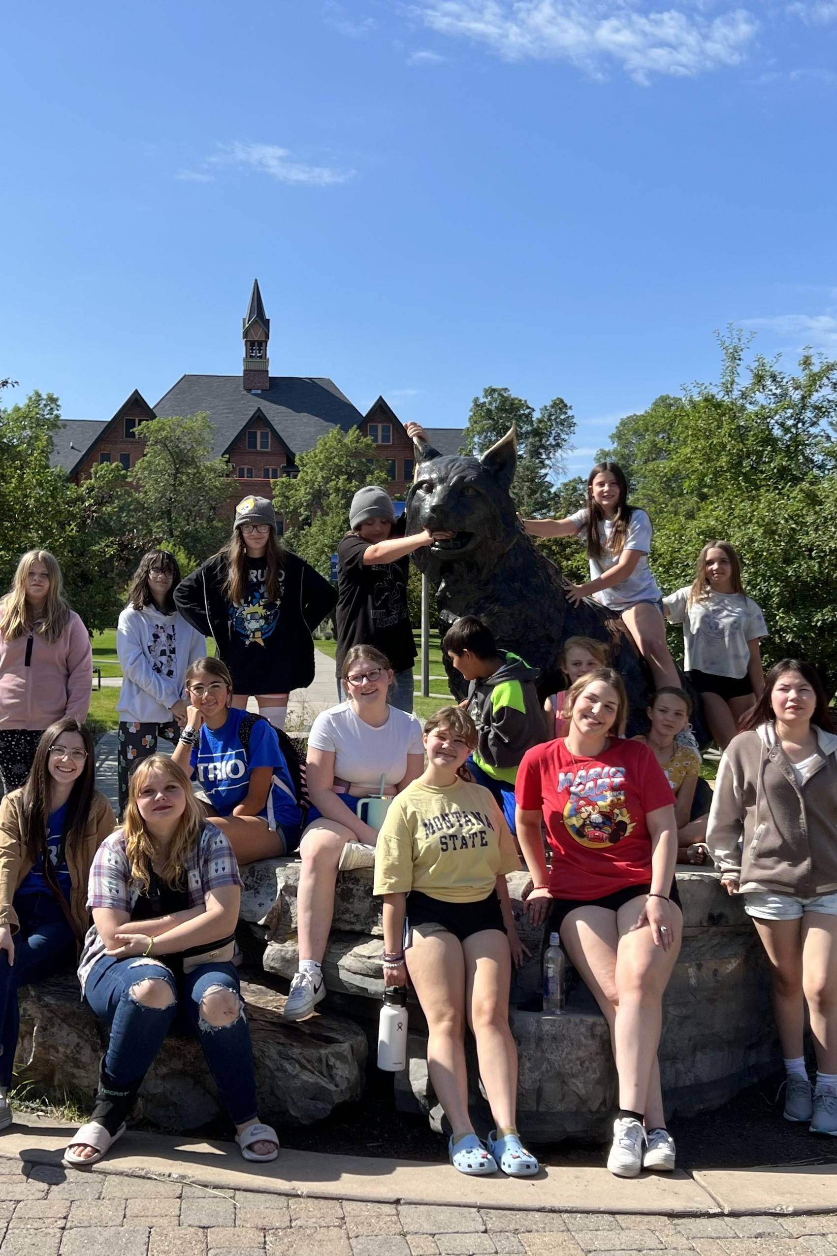 TRIO students pose around a black cat statue on a TRIO outing